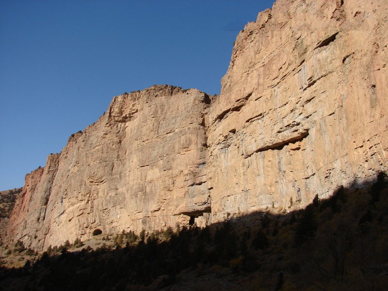 Amir Temir Cave faces on the canyon wall. Two cave mouths can be seen at the base of the canyon wall